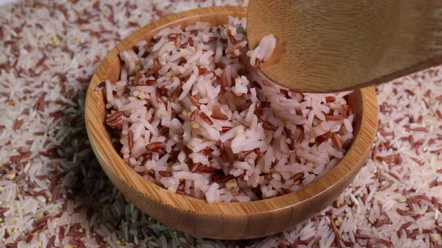 Cooked and raw mixed low glycaemic index healthy rice grain basmati millet buckwheat red rice in wooden bowl spoon bed of rice
