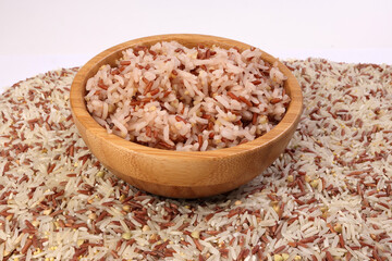 Fototapeta na wymiar Cooked and raw mixed low glycaemic index healthy rice grain basmati millet buckwheat red rice in wooden bowl bed of rice over white background