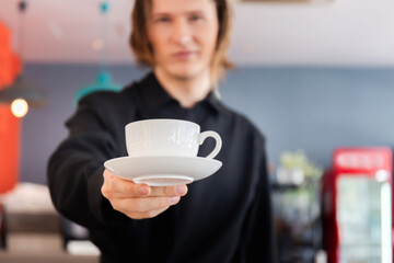 White coffee cup in barista man hand, Smiling man holding white cup of coffee