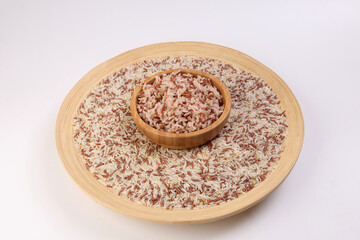 Cooked and raw mixed low glycaemic index healthy rice grain basmati millet buckwheat red rice in wooden bowl over wooden plate on white background