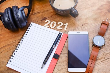 Empty notebook with, smartphone, men wristwatch, a cup of coffee, and headphone on the wooden table 