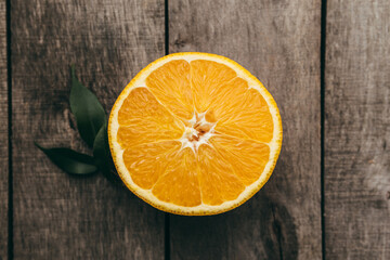 Sliced halves of orange fruit on gray wooden background. Pulp and green leaves