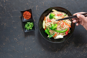 Hand uses chopsticks to pickup tasty  Vegetarian Noodles Thai vegetarian vegetables noodles in a...