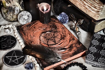 Magic grimoire of spells, black candles, tarot cards and pentagram on witch table.