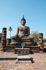 Fototapeta premium Ruins of ancient temples, only bricks and old Buddha statue in the Sukhothai Historical Park.
