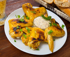 Crispy grilled chicken wings served with spicy sauce on white plate