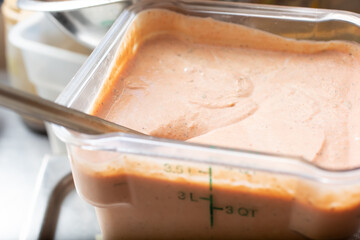 A view of a large container of thousand island dressing, in a restaurant kitchen setting.