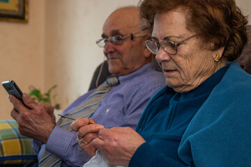 older couple at home entertaining knitting and with mobile phone