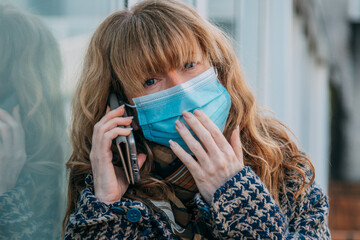 woman with mask and mobile phone in the street outdoors