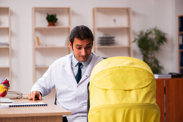 Young male doctor looking after new born in the clinic