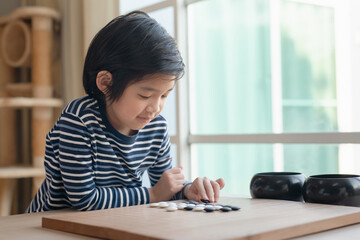 Cute Asian boy learned to play Chinese go game