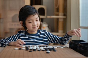 Cute Asian boy learned to play Chinese go game