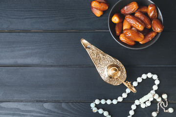 Aladdin lamp of wishes with tasbih and dates on dark wooden background