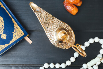 Aladdin lamp of wishes, Koran and tasbih on dark wooden background