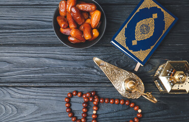 Aladdin lamp of wishes, Koran, tasbih and dates on dark wooden background