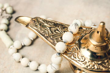Aladdin lamp of wishes and tasbih on grey background, closeup
