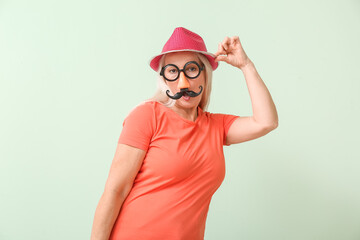 Mature woman in funny disguise on color background. April Fools Day celebration