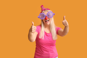 Mature woman in funny disguise showing thumb-up on color background. April Fools Day celebration
