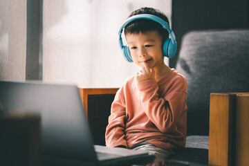 Asian boy watching and listening with laptop at home, using application online virtual class , social distancing, homeschooling, learning remotely during covid-19 coronavirus pandemic.