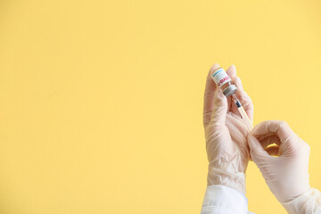 Doctor's hands with vaccine against COVID-19 on color background