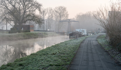 An inland vessel lies in the river on a foggy morning
