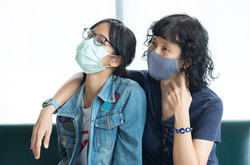 Asian mother and daughter live close to each other. But always wear a mask