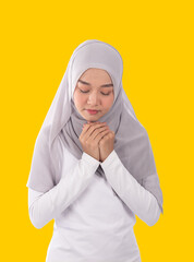 Portrait of Muslim woman in cool earth tone hijab and traditional clothes praying for Allah by close her eyes, isolated white background.