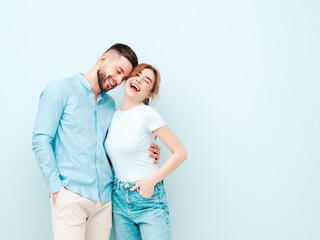 Naklejka premium Smiling beautiful woman and her handsome boyfriend. Happy cheerful family having tender moments near light blue wall in studio.Pure cheerful models hugging.Embracing each other
