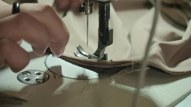 Closeup of a woman's hands with manucure sewing fabric with a sewing machine. Women's hands sew on a sewing machine. Fashion, creation and tailoring.