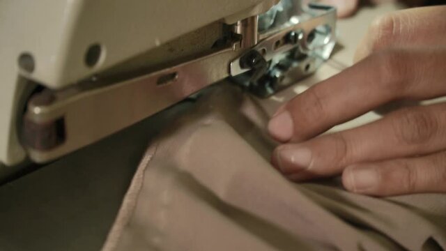 Closeup of a woman's hands with manucure sewing fabric with a sewing machine. Women's hands sew on a sewing machine. Fashion, creation and tailoring.