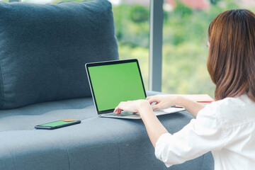 Woman working from home on laptop online meeting in home office. Entrepreneur asian business woman using notebook laptop sit on sofa technology new normal lifestyle. Happy woman typing keyboard laptop