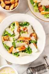 Caesar salad, shot from above on a white marble background