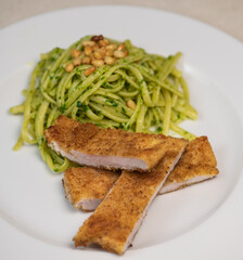 Turkey cutlet and Green spinach spaghetti with cheese and tomato on table