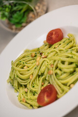 Green spinach spaghetti with cheese and tomato on wooden table