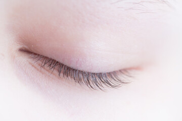 closed human eye. Closed eyelid with eyelashes. Indoor photo with shallow depth of field.