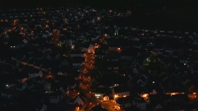 Citynight aerial view of Albstadt in the recreation aera of the Swabian Alb in germany. Zoom out from a illuminated crossing with driving cars to an overview over the dark city with lots of houses.