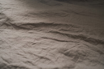brown crumpled linen bed cover with sunlight from window