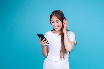 Music and entertainment concept of Asian woman wearing headphones listening to music sound to mobile smart phone device, smiling happy enjoying lifestyle, blank white blue banner isolated background