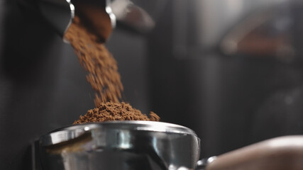 freshly ground coffee falls into portafilter from grinder closeup