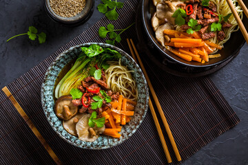 Asia style ramen soup with udon noodle, beef, shiitake, pak choi cabbage and carrots