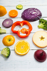sliced fruit and vegetable circles on white wood table