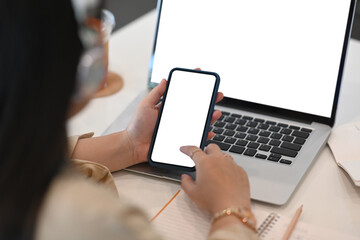 Young woman office worker sitting in front of computer laptop and using mobile phone.