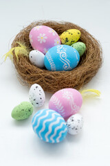Easter holiday. Festive composition. Holiday decoration. Pastel color painted eggs with traditional and modern ornament feather in nest isolated on white background.
