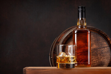 Scotch whiskey bottle, glass and old barrel