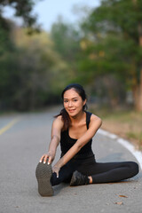 Fitness woman stretching her body in the park before fitness training session at the park.