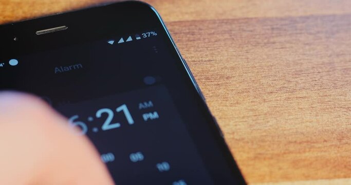 Man inputs twenty minutes in timer app on contemporary mobile phone with black screen by finger on table extreme close view