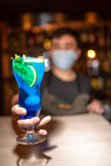 Barman serving blue lagoon cocktail