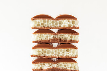 Sweet stack of different kind porous chocolate pieces on white background