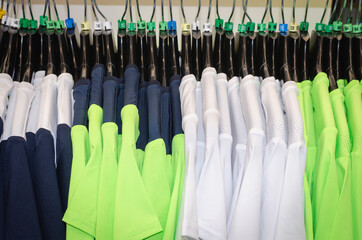 Multicolored sports t-shirts on hangers in the store.