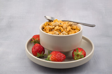 bowl of corn flakes cereals and spoon isolated on grey background.